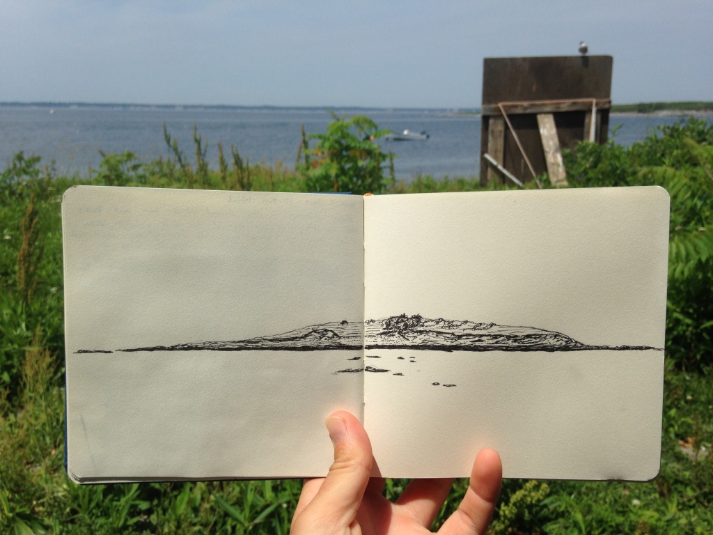 Photo of sketchbook with a pen drawing of an island and ocean in the background
